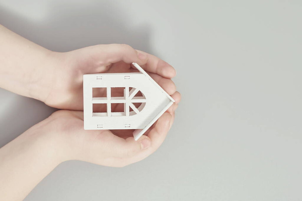 Hand holding a house model. Buy and rent house concept. Grey background. - Фото, изображение