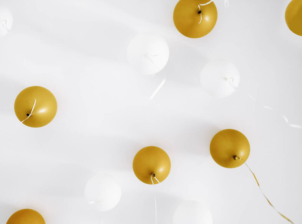 Διακοπές λευκό και χρυσά μπαλόνια κρέμονται κοντά στο κιγκλίδωμα, σπίτι πάρτι γενεθλίων, εορταστική φόντο - Φωτογραφία, εικόνα