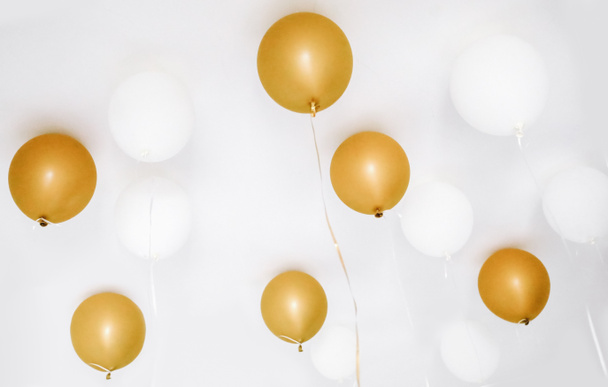 Helium golden and white ballons flying on room seling, festive party minimalistic background - Photo, Image