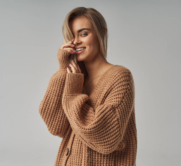 Close up portrait of a young blonde woman in brown wool sweater - Foto, Imagen