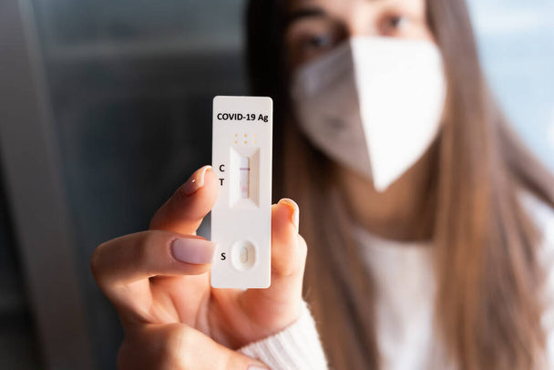 Vrouw met masker met een negatieve zelftest met negatief resultaat. Corona virus - Covid-19 snelle test. jong tiener meisje. - Foto, afbeelding