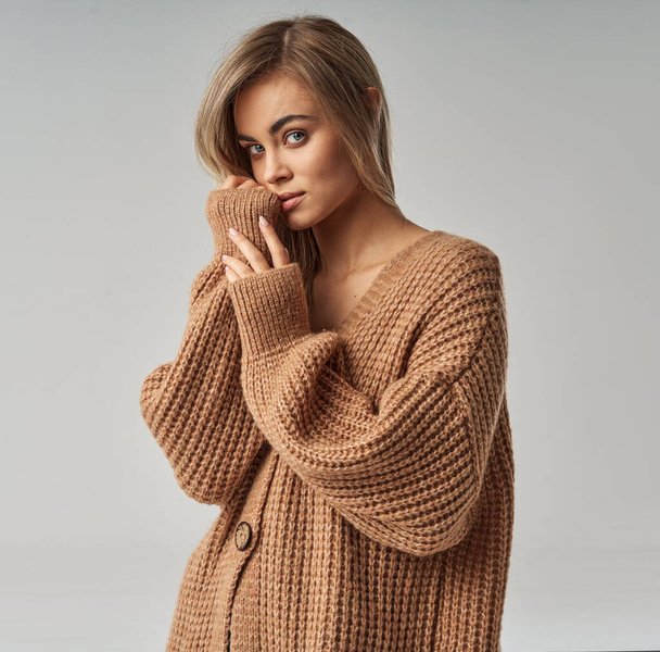 Close up portrait of a young blonde woman in brown wool sweater - Foto, imagen