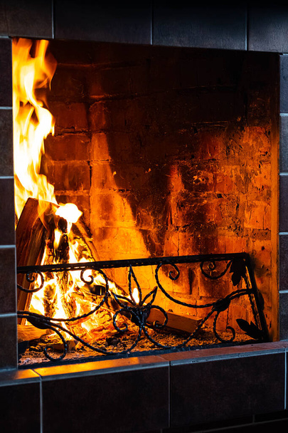 Quema la chimenea, de cerca. Ambiente acogedor vista frontal de otoño o invierno por la noche. Fuego abierto con llamas reales, leña ardiendo en la chimenea. - Foto, imagen
