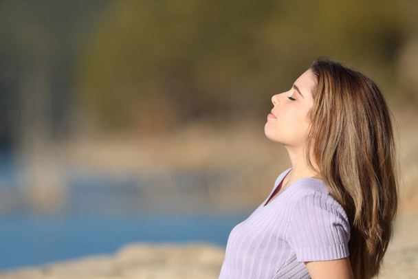 Side view portrait of a relaxed teen breathing fresh air sitting in a lake - Foto, Imagem