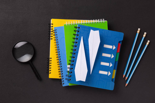 Egy halom színes jegyzetfüzet egy diákról vagy egy iskolás diákról fekete táblán, másolási hellyel egy vissza az iskolába koncepcióban. - Fotó, kép