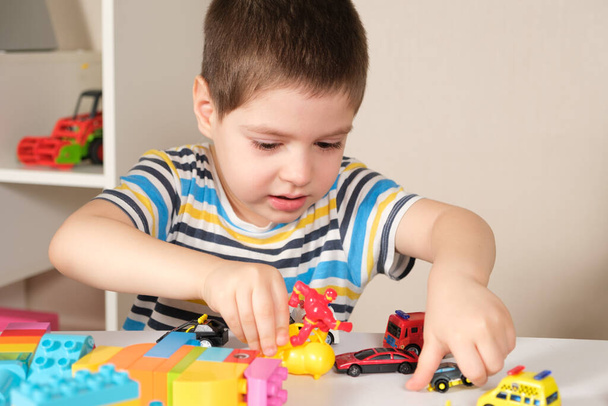 Красивий хлопчик 4 років грає з машинами та будівельним майданчиком, ігри дітей дошкільного віку, розвиток уяви
. - Фото, зображення