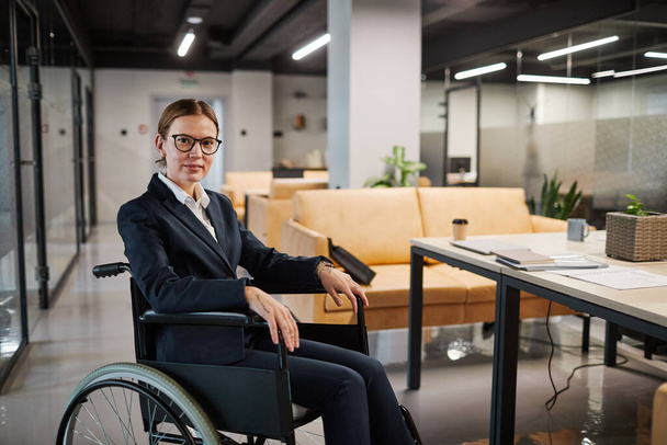 Бизнесвумен, использующая инвалидное кресло в современном офисе - Фото, изображение