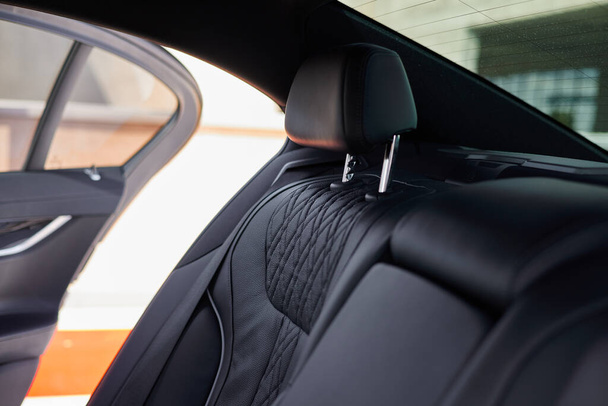 Black leather rear seat of a luxury car. The door slightly ajar. - Φωτογραφία, εικόνα
