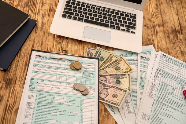 white notebook tax form usa 1040 with dollar bills and coins laid out on a wooden table. Business concept - Foto, imagen