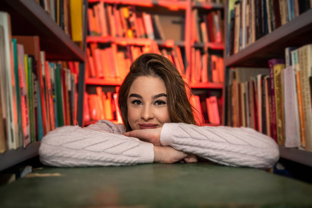 Katı siyah giysiler içinde, kütüphanede kitap okuyan genç ve güzel bir bayan profesör. Kütüphane konsepti - Fotoğraf, Görsel