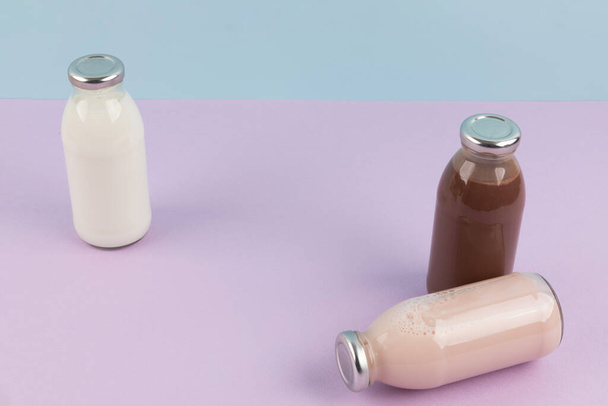white milk, strawberry milk, chocolate milk in a sky blue and purple background - Zdjęcie, obraz