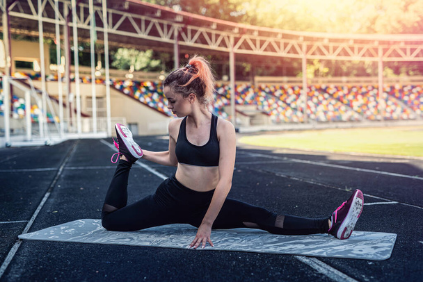 female trainer doing yoga or pilates exercise against green stadium background. Active Lifestyle, healthy - Fotografie, Obrázek