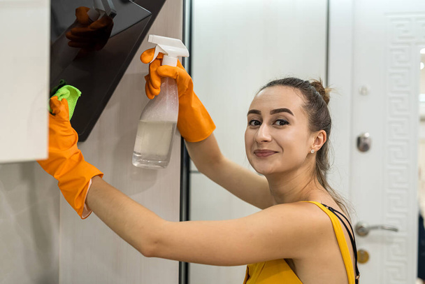 Kaunis ja nuori nainen puhdistaa keittiön huppu pölystä - Valokuva, kuva