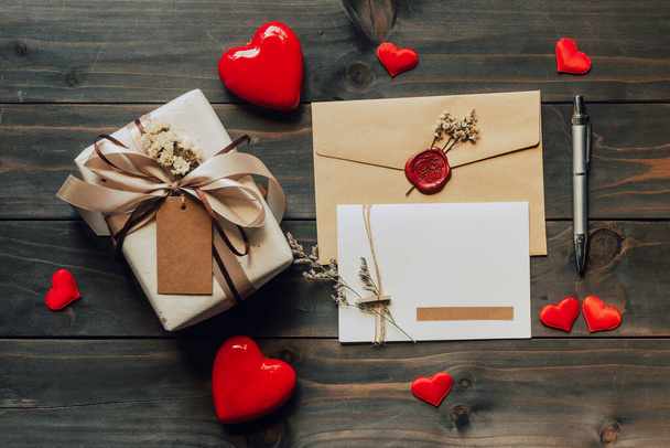 バレンタインデーの木製テーブルの上に弓リボンと紙の心を持つギフトボックスとグリーティングカード。コピースペース. - 写真・画像
