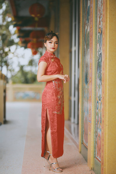 Schöne asiatische Chinesin trägt traditionelles rotes Kleid Cheongsam Fashion Posting Chinese Lunar New Year. - Foto, Bild