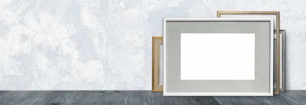 Falsificazione di una cornice bianca su una mensola di legno o un tavolo sullo sfondo di una parete - Foto, immagini