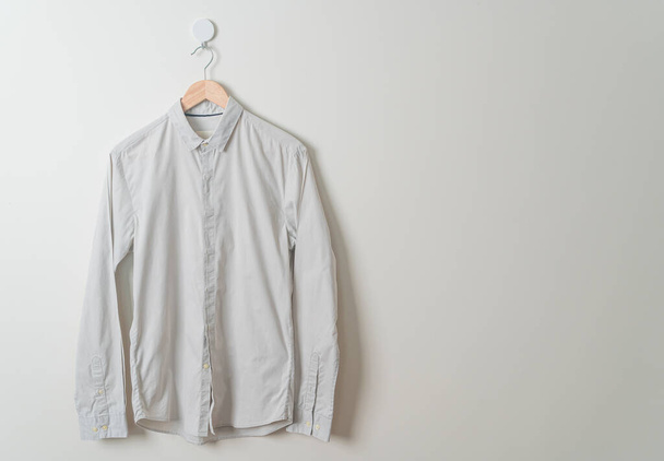 hanging beige shirt with wood hanger on wall - Photo, image
