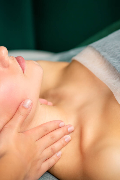 Масаж жіночої шиї. Молода біла жінка отримує масаж шиї, розслабляючись у спа-салоні
 - Фото, зображення