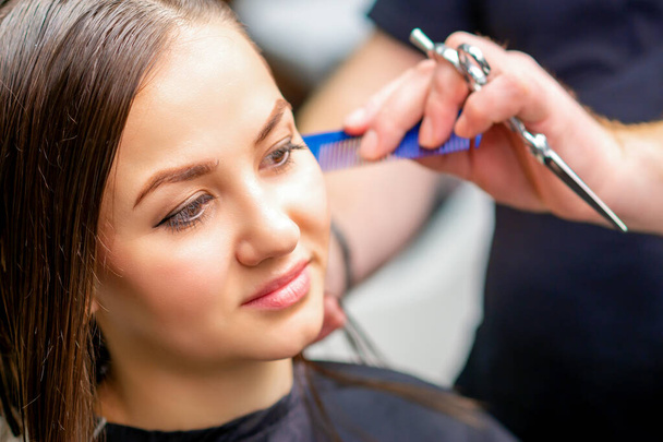 Styling ženské vlasy. Muž kadeřník dělá účes pro mladou ženu v salonu krásy - Fotografie, Obrázek