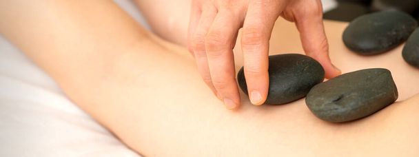Uma mulher recebendo spa terapia de pedra quente pernas massagem procedimento em um salão de beleza - Foto, Imagem