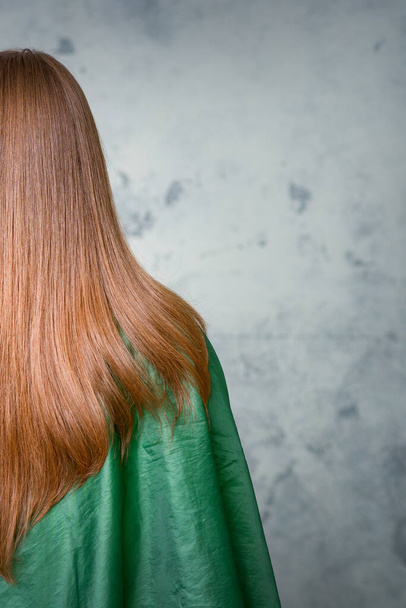 Taustakuva naisesta, jolla on pitkät ruskeat hiukset harmaata taustaa vasten - Valokuva, kuva