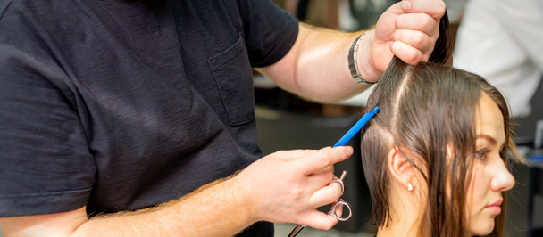 Parrucchiere divide i capelli femminili in sezioni con pettine tenendo i capelli con le mani nel salone di parrucchiere da vicino - Foto, immagini