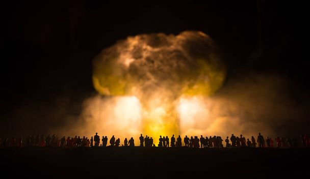 Atomkriegskonzept. Explosion einer Atombombe. Kreative Dekoration der Kunstwerke in Dunkelheit. Die Menschen schauen auf eine riesige Pilzwolke aus Atombomben. Selektiver Fokus - Foto, Bild