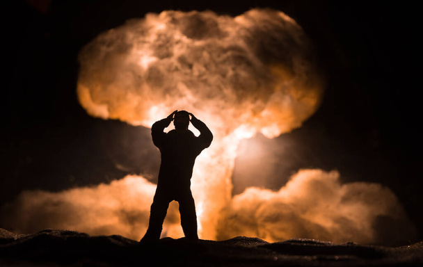 Концепция ядерной войны. Взрыв ядерной бомбы. Творческое художественное оформление в темноте. Силуэт человека против гигантского грибного облака атомного взрыва. Селективный фокус - Фото, изображение