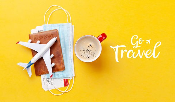 Travel and vacation concept. Airplane toy over passport with tickets and face mask. Trip accessories and items. Top view flat lay - Fotoğraf, Görsel
