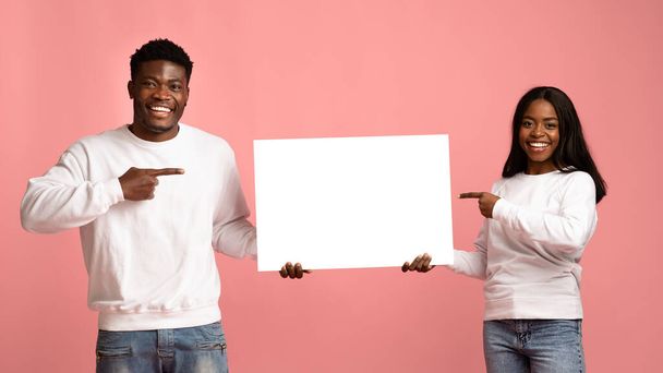 Happy black couple pointing at advertising board in their hands - Fotoğraf, Görsel