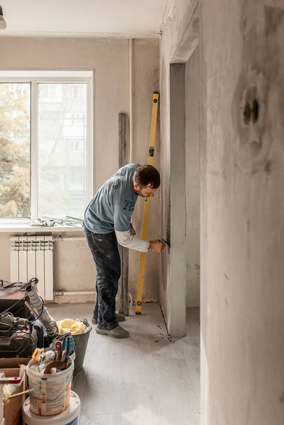 Muž-mistr evropského vzhledu omítá zdi, provádí opravy v bytě, koncept opravy a přestavby domu - Fotografie, Obrázek