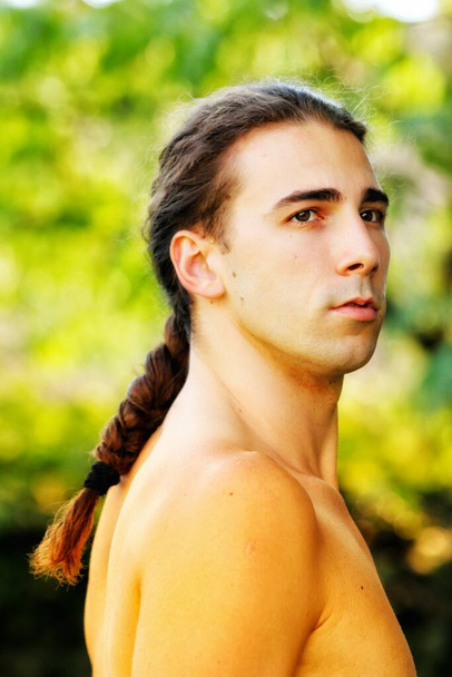 Atraktivní chlap s velmi dlouhými vlasy pózuje v divočině. Koncept modelování a módy. - Fotografie, Obrázek