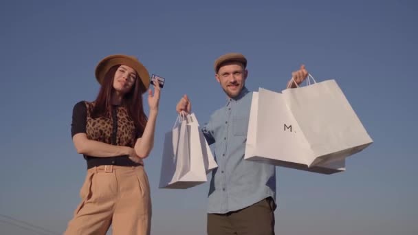 Χαρούμενο ζευγάρι με πιστωτική κάρτα και τσάντες για ψώνια - Πλάνα, βίντεο