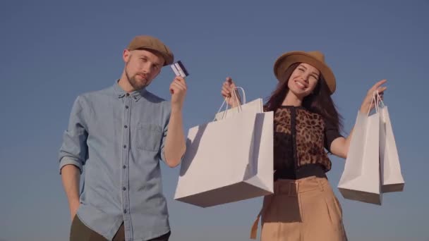 Μοντέρνο ζευγάρι με πιστωτική κάρτα και τσάντες για ψώνια - Πλάνα, βίντεο
