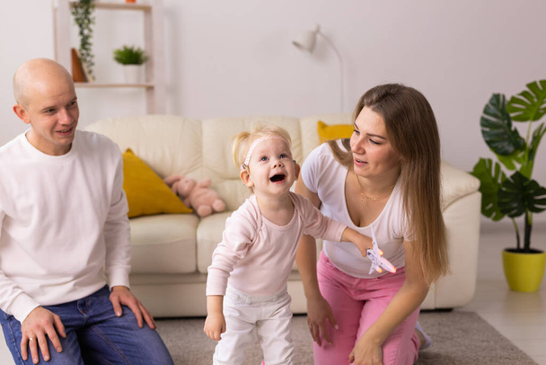 Kind mit Cochlea-Implantaten hat Spaß mit Mutter und Vater zu Hause. Gehörlosigkeit und medizintechnisches Konzept. - Foto, Bild