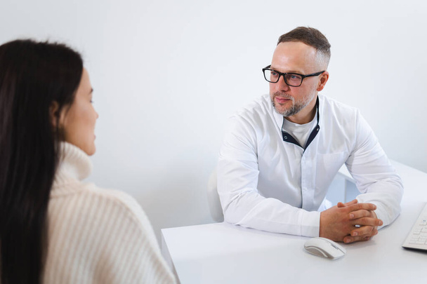 Médico varón hablando con paciente mujer en el consultorio - Foto, Imagen
