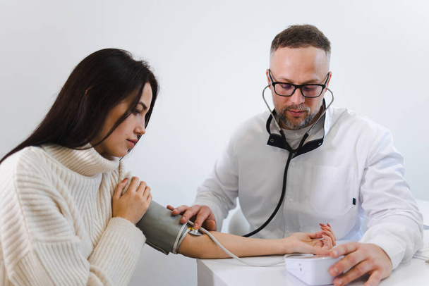 診察時の男性医師は女性患者の血圧を測定します。心臓病専門医の女性 - 写真・画像