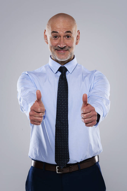 Feliz hombre de negocios vistiendo camisa y corbata mientras está de pie en aislado fondo gris claro y dando pulgares hacia arriba. - Foto, Imagen