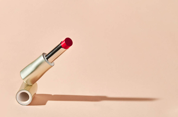 Red lipstick on beige background. Copy space. Beauty and makeup background.  - 写真・画像