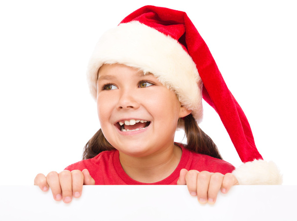 Little girl in santa hat is holding blank board - Fotografie, Obrázek
