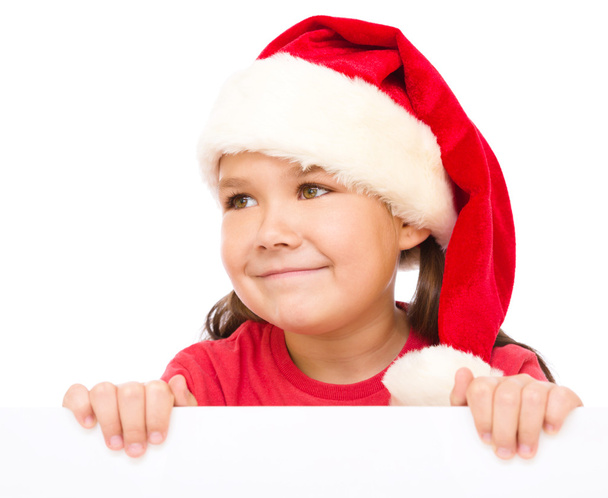 Little girl in santa hat is holding blank board - Fotó, kép