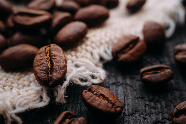 Makrofotografia ziaren kawy leży na teksturowanym drewnie i kory. Świeże zbiory aromatycznej kawy. Skupienie selektywne. - Zdjęcie, obraz