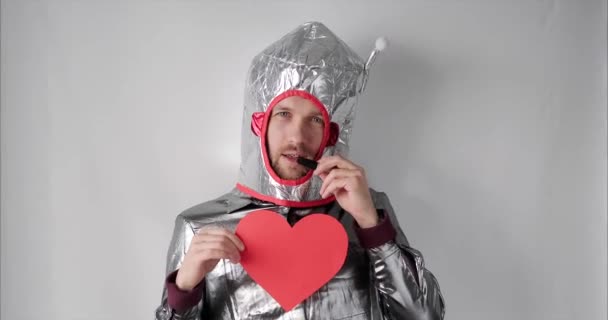 Aranyos férfi asztronauta jelmezben piros papír szív alakú - Felvétel, videó