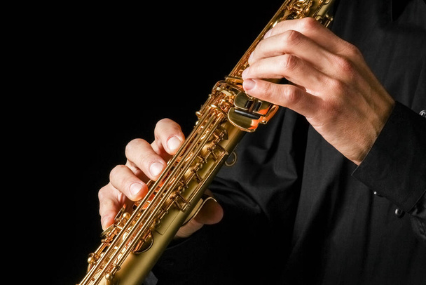 soprano saxophone in hands on a black background - 写真・画像