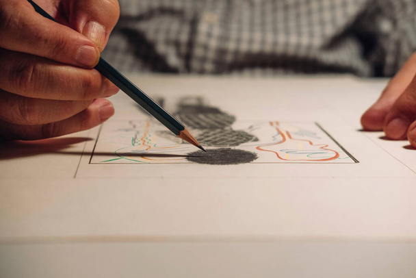 Primer plano de la mano de un hombre sosteniendo un lápiz mientras dibuja un dibujo. Concepto de actividades para ancianos. - Foto, Imagen