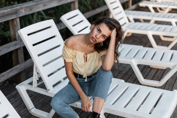 Kauneus nuori nainen hipster muodissa rento kesävaatteet istuu ja levätä solariumissa puinen laituri - Valokuva, kuva