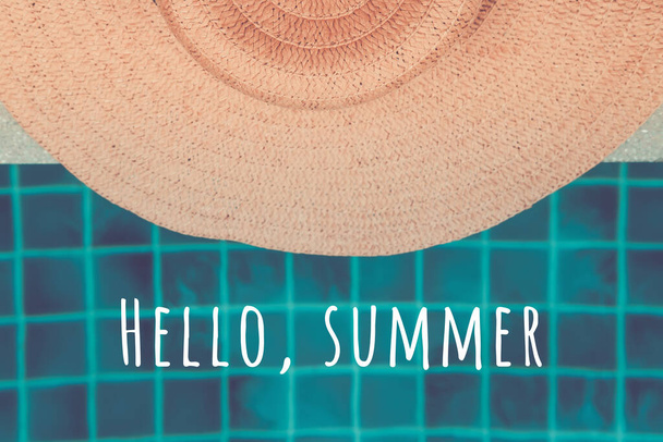 Stro hoed aan de rand van het zwembad met Hello zomer formulering - Foto, afbeelding