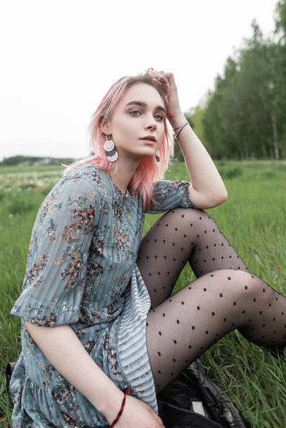 Csinos fiatal nő rózsaszín haj elegáns kék ruha fekete vintage harisnya ül a friss zöld fű szabadban a természetben. Vonzó lány divat modell elegáns ruhák nyugszik a városon kívül. - Fotó, kép