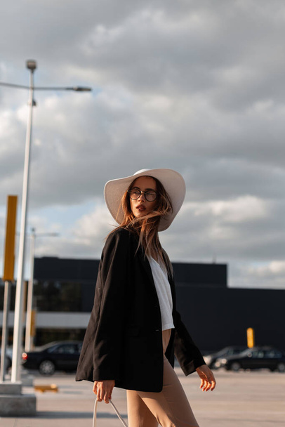 Mujer joven con estilo en sombrero vintage en ropa de moda de negocios posando en la ciudad en el día soleado. Bella dama. Ropa elegante de moda para mujeres. - Foto, Imagen