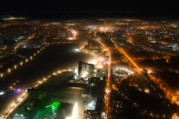Aerial view of high rise apartment buildings and bright illuminated streets in Ivano-Frankivsk city, Ukraine residential area at night. Dark urban landscape - Photo, Image
